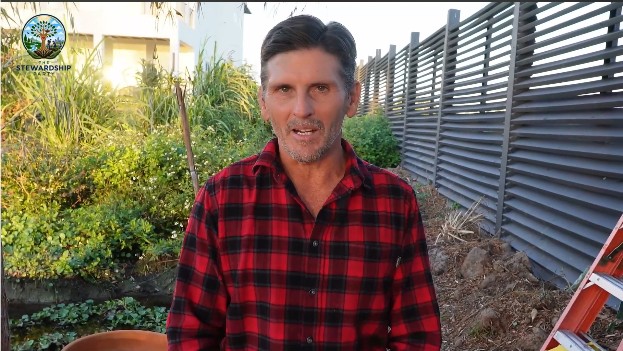 Jim Gale speaking to camera in a garden at golden hour